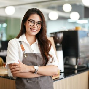 Portrait of a happy waitress standing at restaurant entrance, coffee shop,. Business owner.