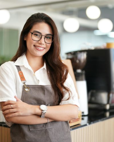 Portrait of a happy waitress standing at restaurant entrance, coffee shop,. Business owner.